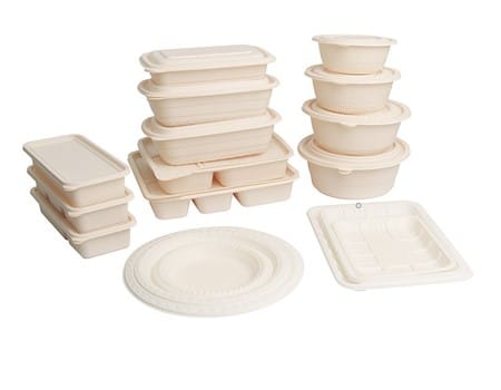 Stacks of beige cornstarch packaging containers in different shapes and sizes